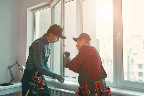 Technician inspecting insulated window fit and perimeter sealing for maximum efficiency, Specialist inspecting damaged window hardware with repair tools and close attention